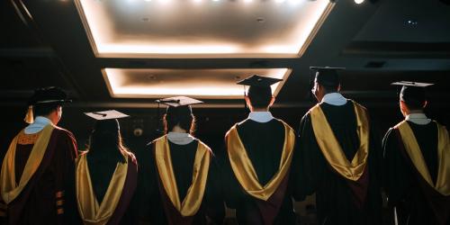 A group of students in graduation cap and gowns standing the stage