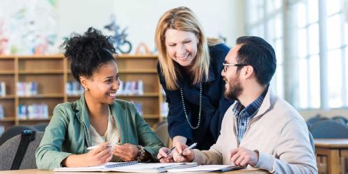Three teachers talking in a library